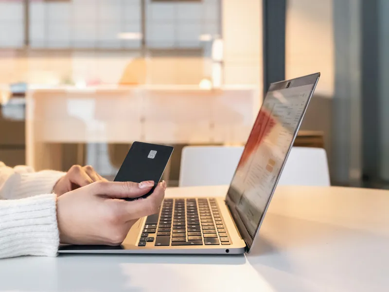 Osoba płacąca kartą płatniczą przy laptopie – księgowość i rozliczanie sklepów internetowych e-commerce
